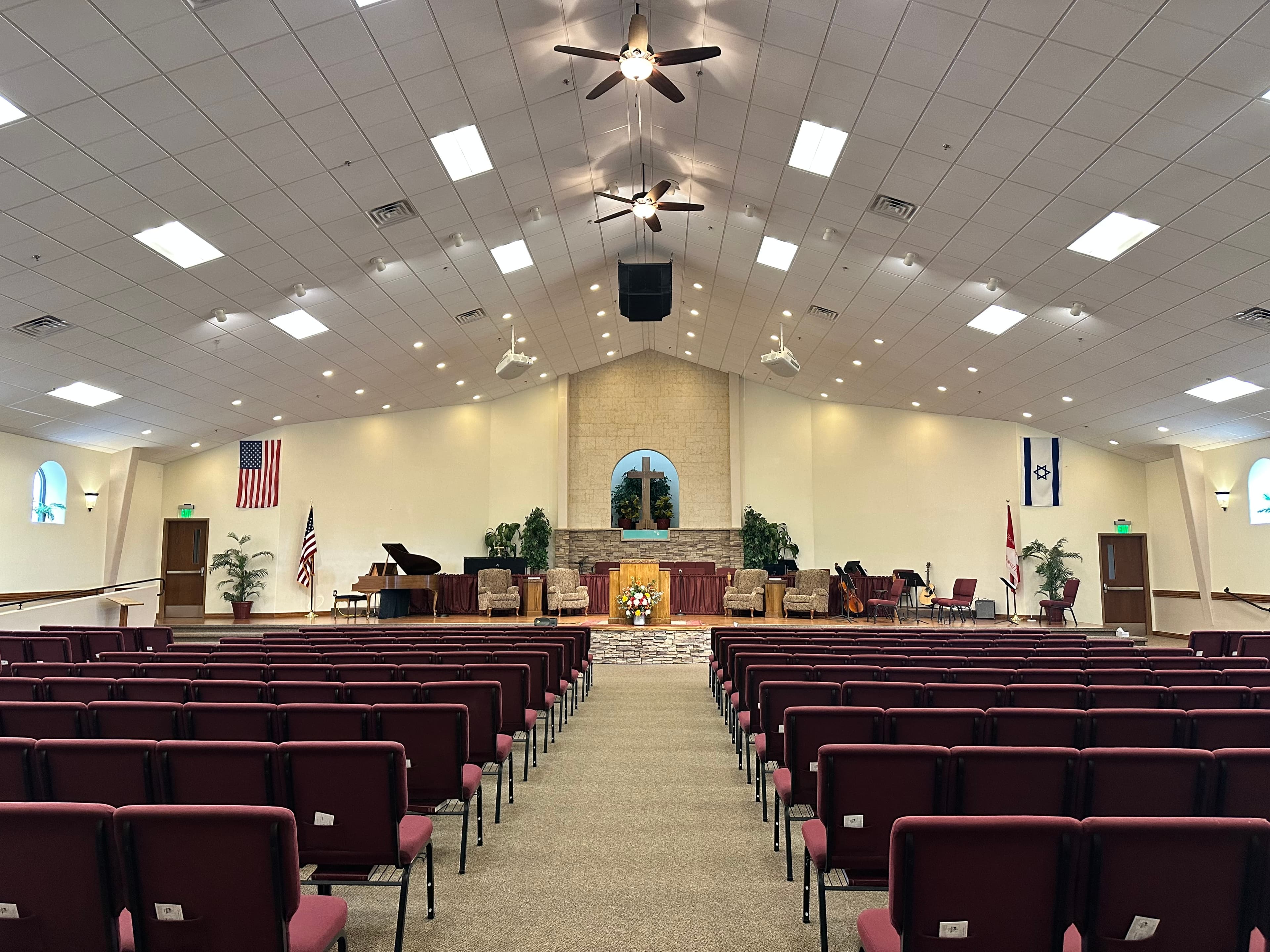 Empty church sanctuary with rows of maroon chairs facing a stage with a wooden pulpit.